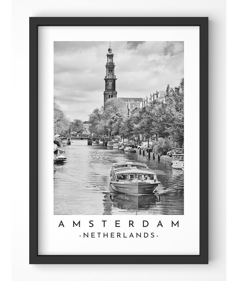 Black and white photograph of Amsterdam cityscape, featuring a canal, bridge, and the Westerkerk church tower.
