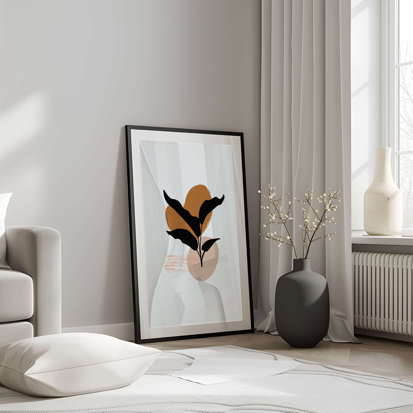 Black-framed black leaf abstract print leaning against a wall in a minimalist room with soft lighting.
