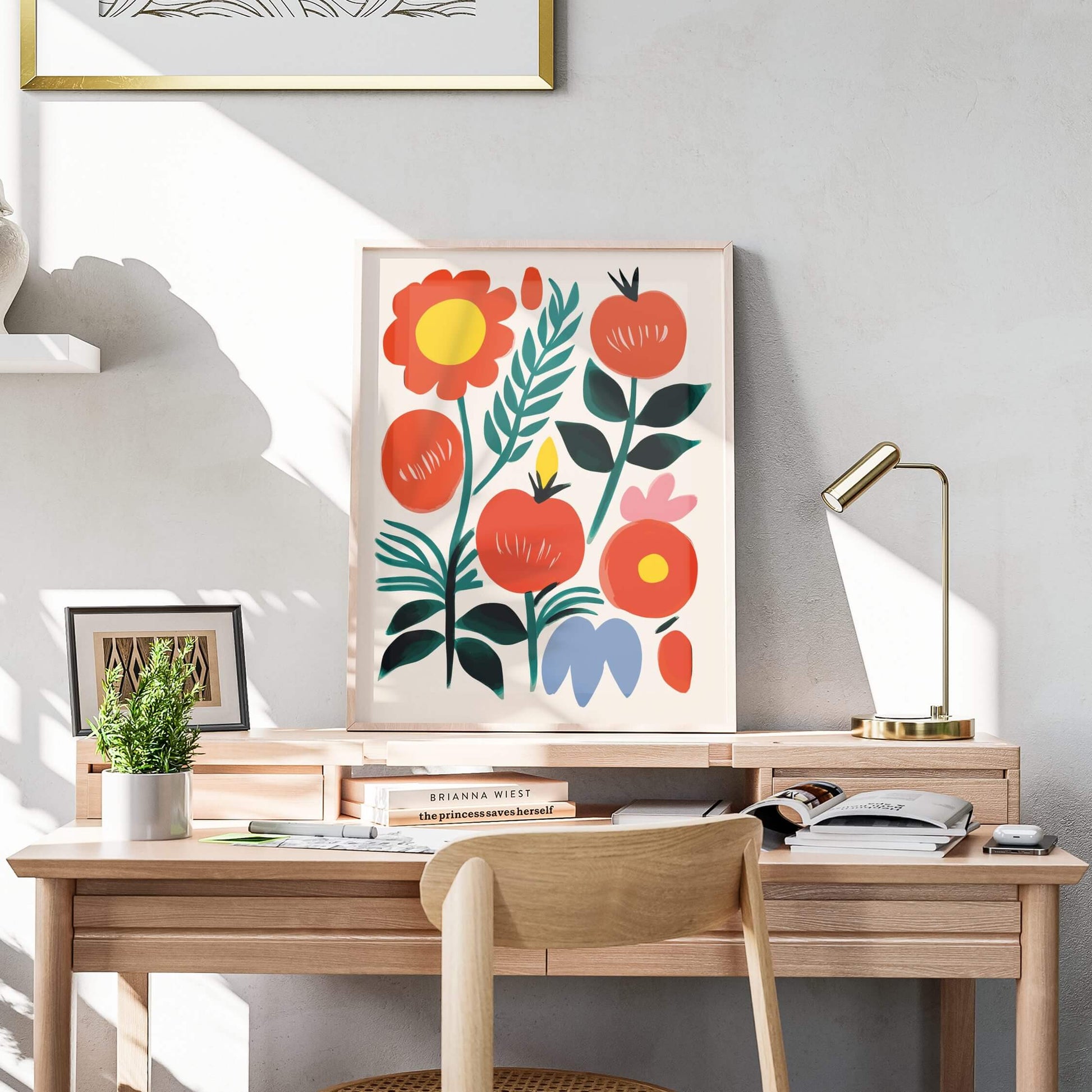 Botanical red fruit print displayed on a desk with natural light, featuring bold colors and abstract floral shapes.
