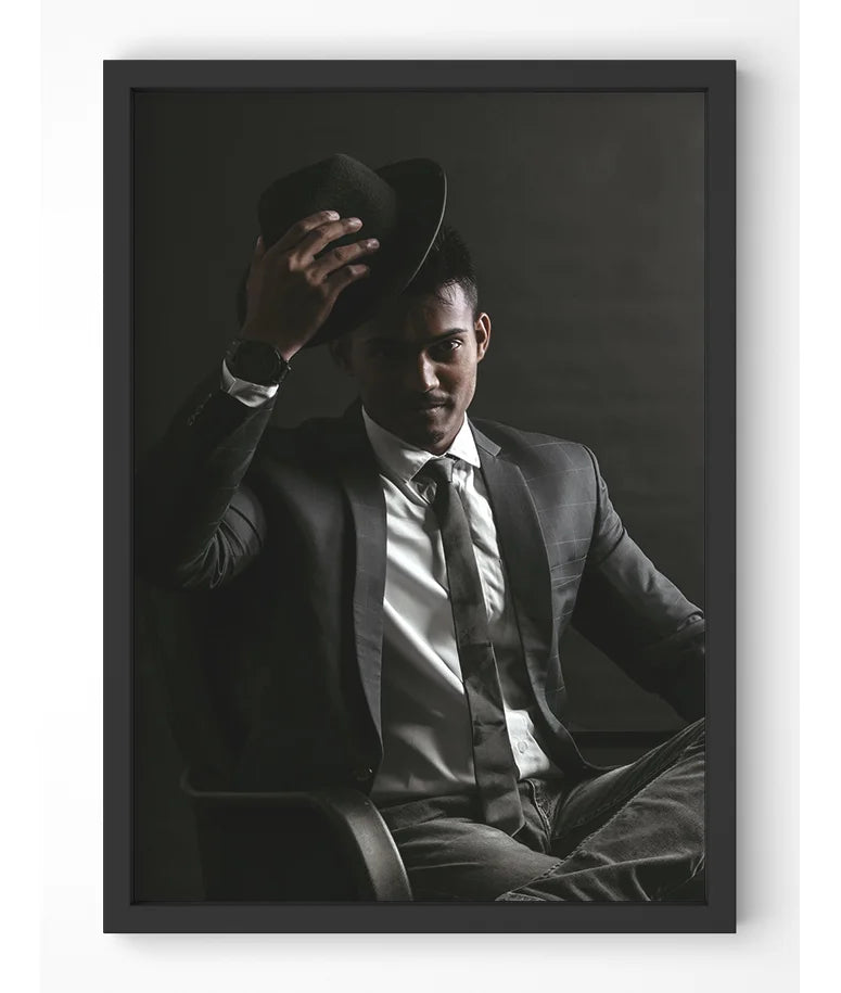 Stylish man in dark suit with fedora against dark backdrop