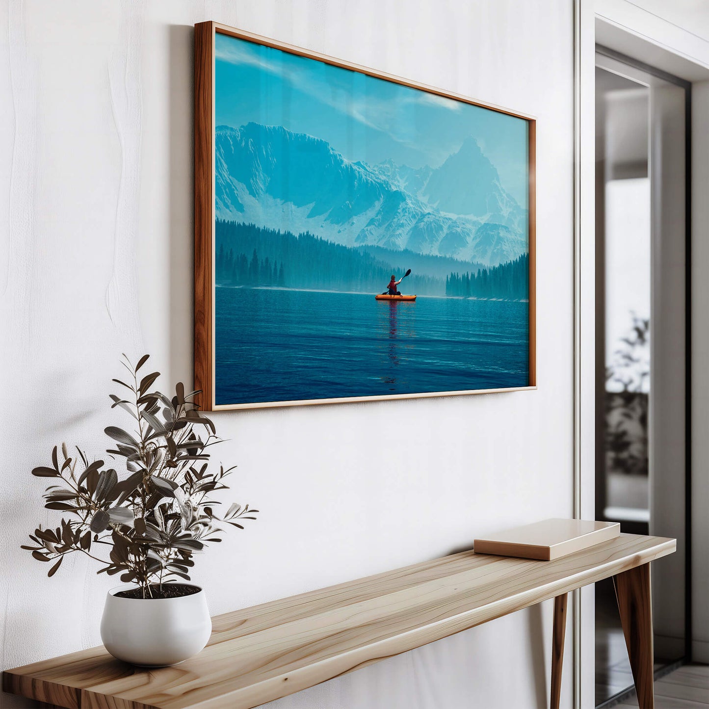 Nature-inspired wall art hanging in a hallway, featuring a lone kayaker on a vast lake.
