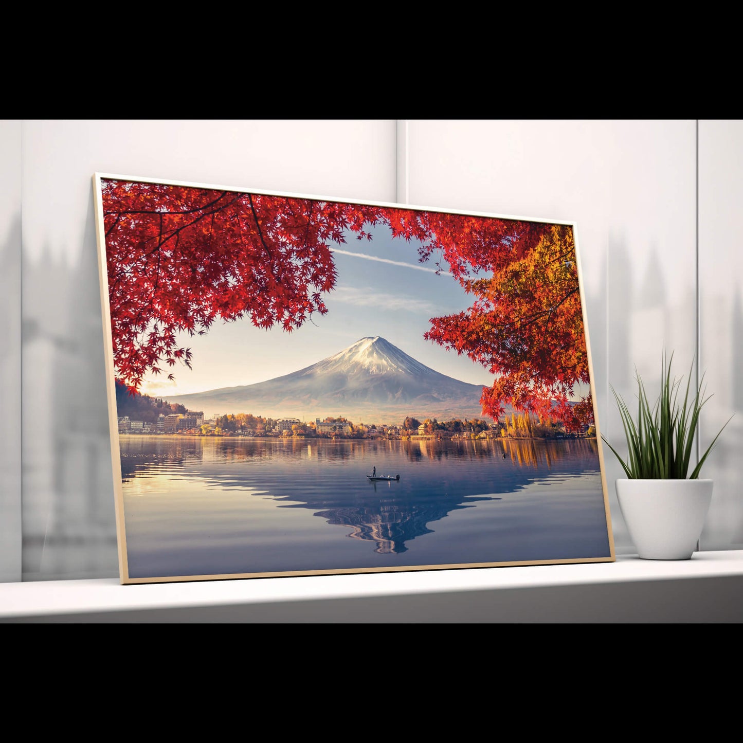 A framed Autumn Fuji print leaning against a wall on a modern shelf, accompanied by subtle decorative pieces.