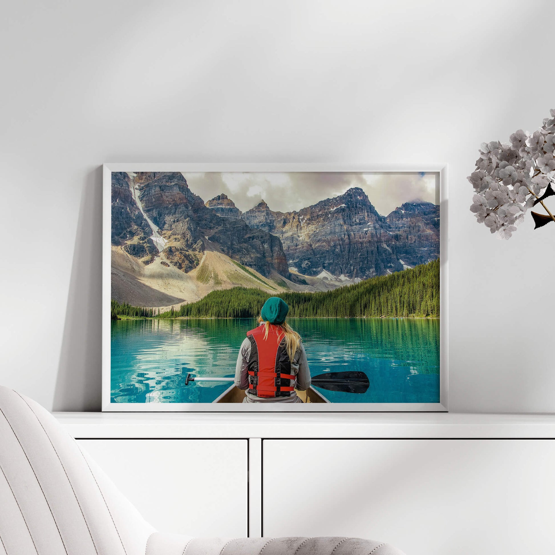 A white-framed Mountain Canoeing Print styled in a minimalist decor setting.