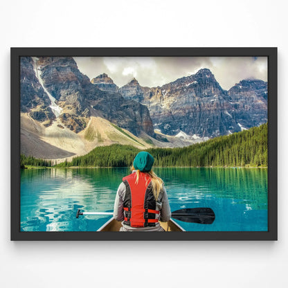A breathtaking art print featuring a woman canoeing on a turquoise mountain lake, surrounded by towering peaks and lush pine forests.