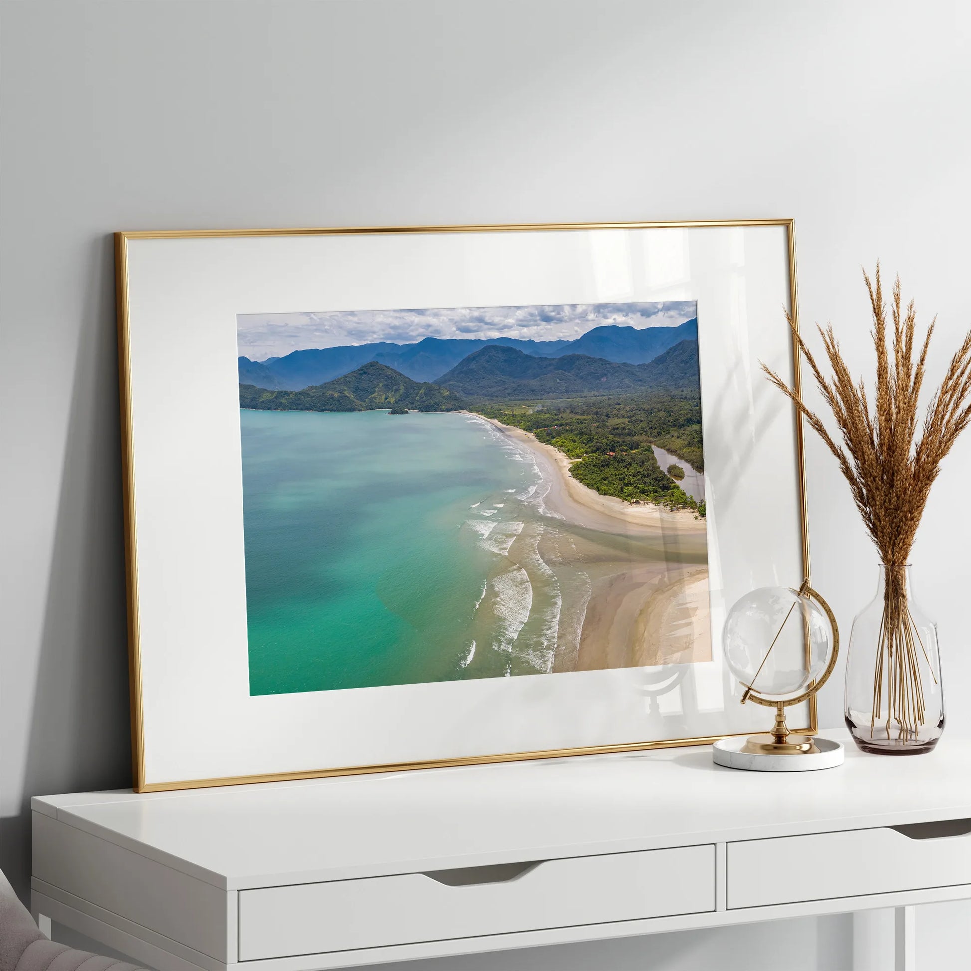 The Tropical Beach Wall Art Print framed and mounted on a bright white wall, adding a serene coastal touch to the space.