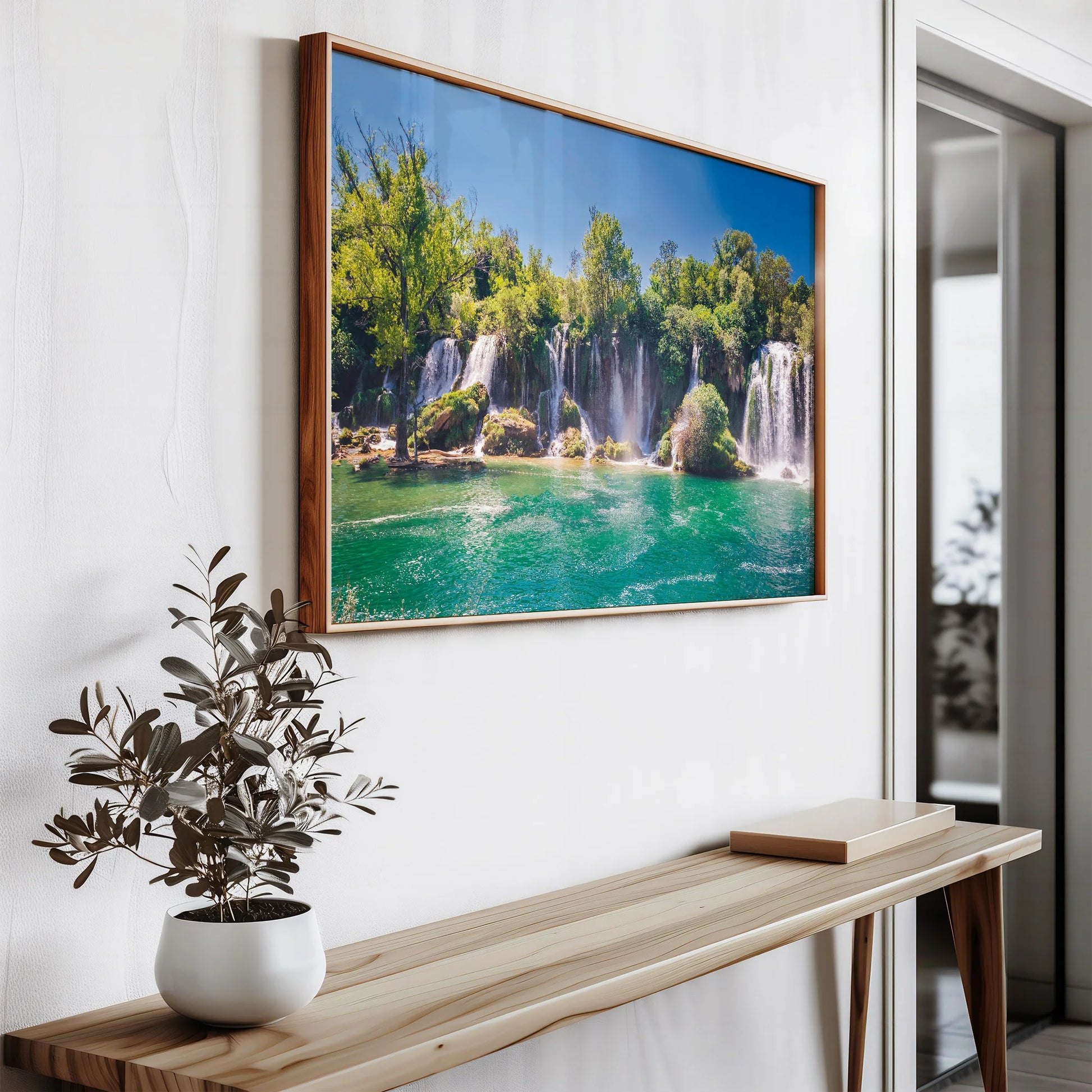 The Waterfall Oasis Print leaning against a white wall on a shelf, ready to be hung in any space.