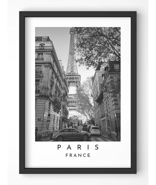 Black and white photograph of the Eiffel Tower framed by Parisian architecture.

