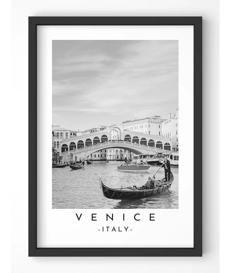 Rialto Bridge and gondolas in Venice depicted in a classic black and white photograph, emphasizing the city's romantic atmosphere.
